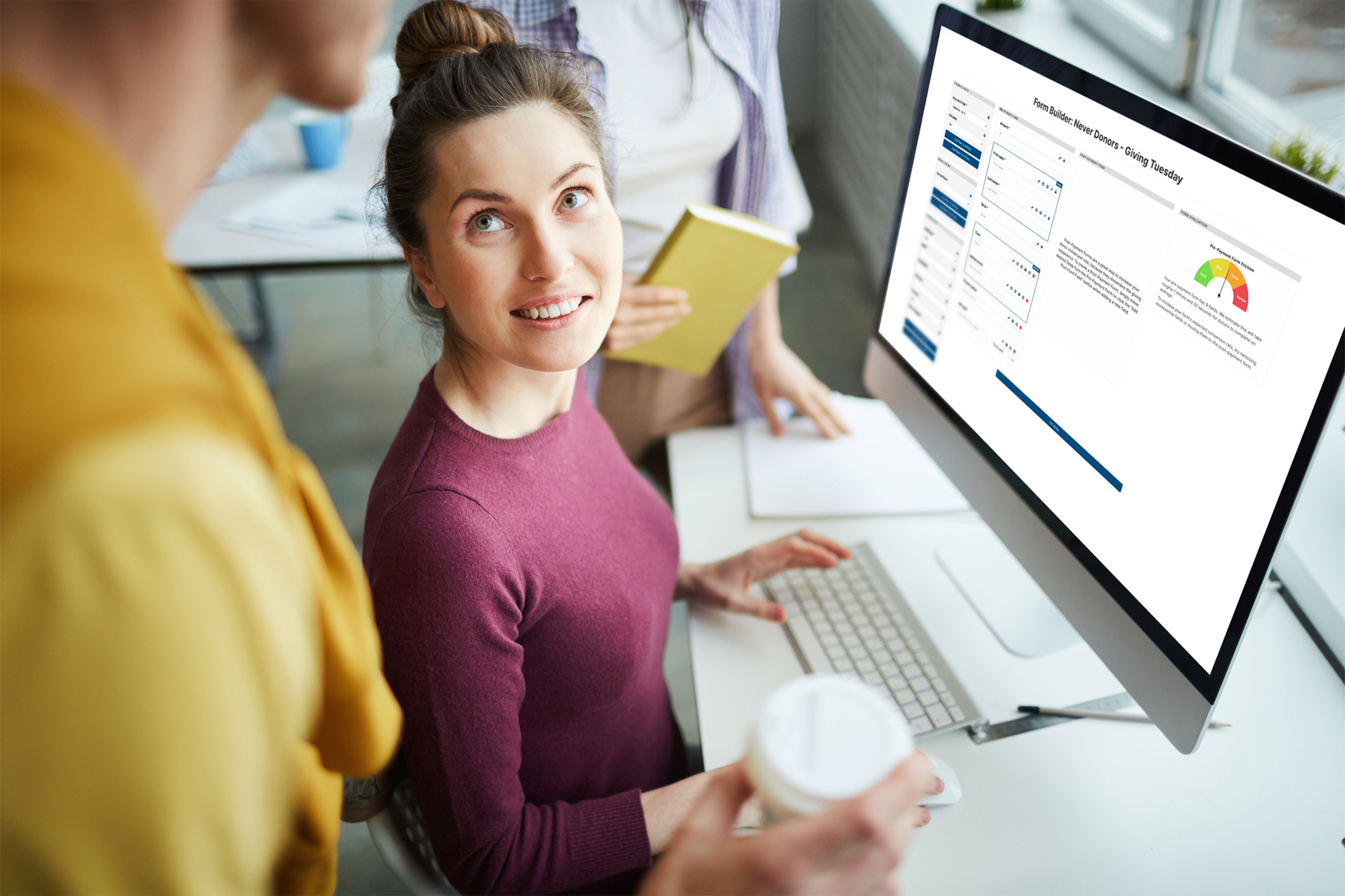 Woman administrator talking to colleague as she builds a custom giving form on the GiveCampus platform.