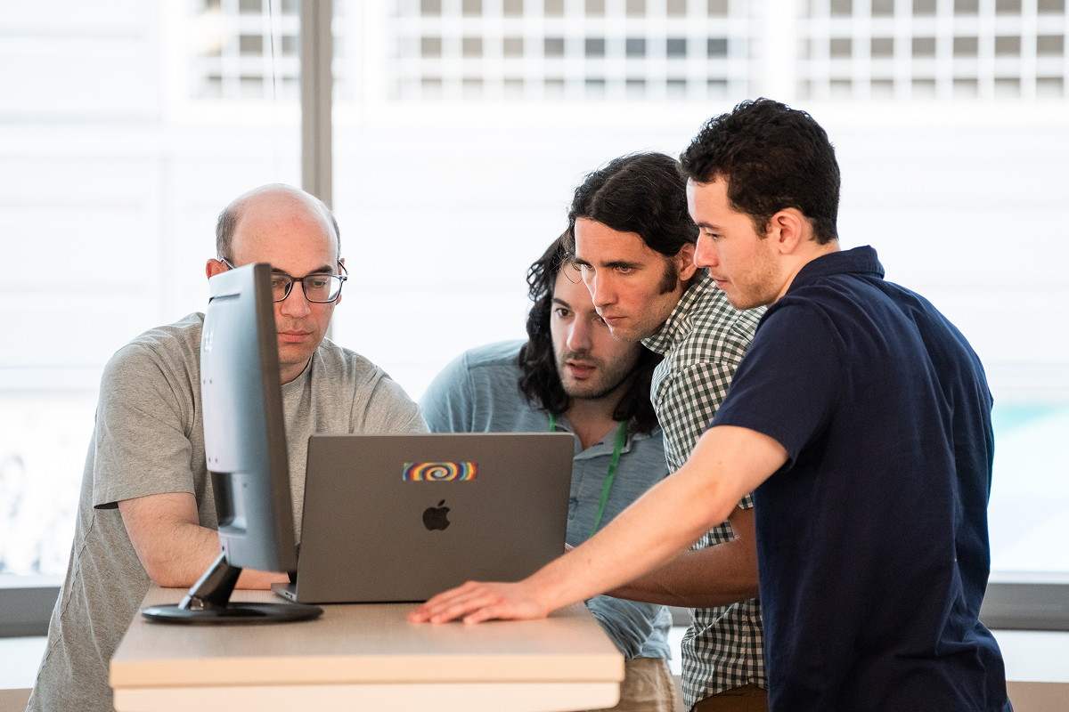 Four members of the GiveCampus Eng team gathered around laptop.